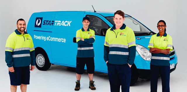 Four StarTrack employees standing in front of a blue StarTrack van.