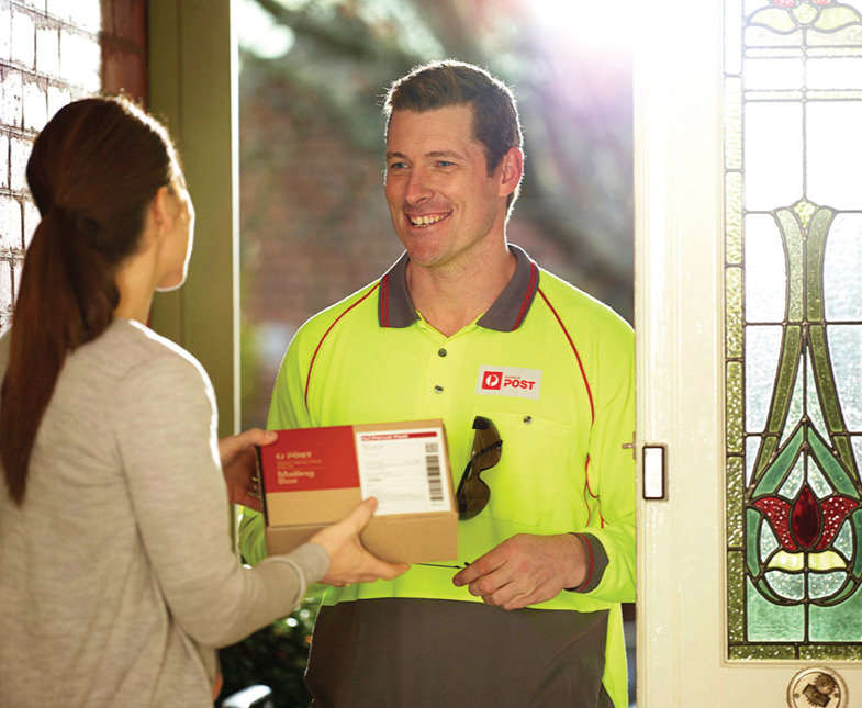 Postie delivering small parcel to woman at her front door