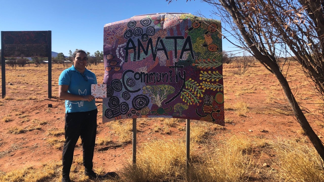 photo-indigenous-woman-standing-next-to-community-sign
