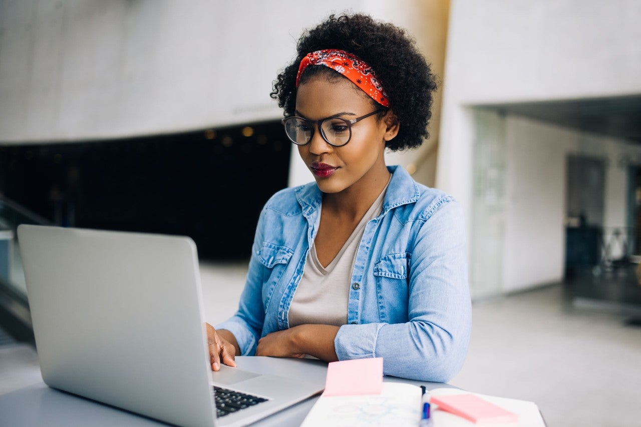 photo-woman-sitting-at-desk-working-on-laptop