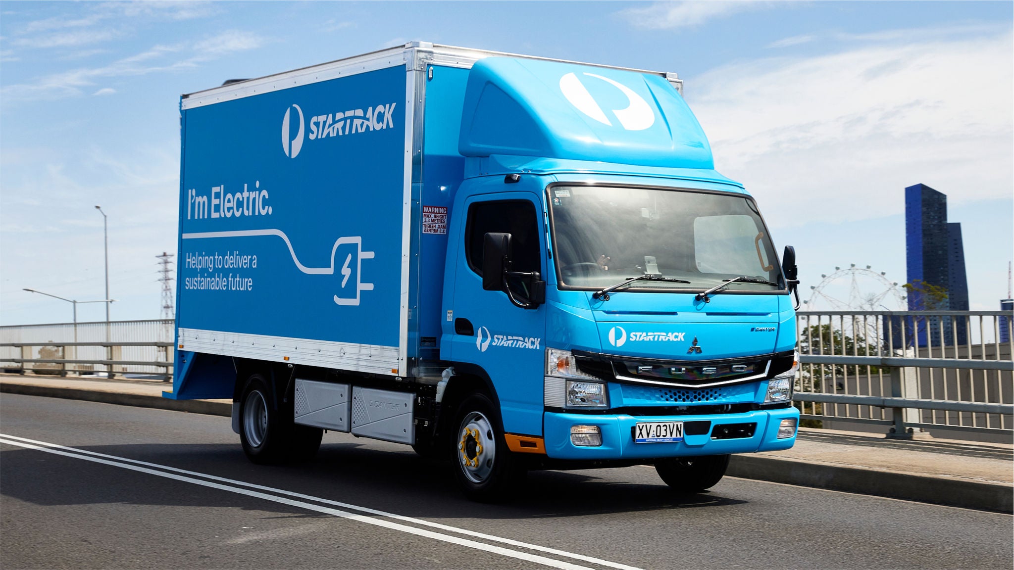 Blue electric StarTrack delivery truck on bridge roadway