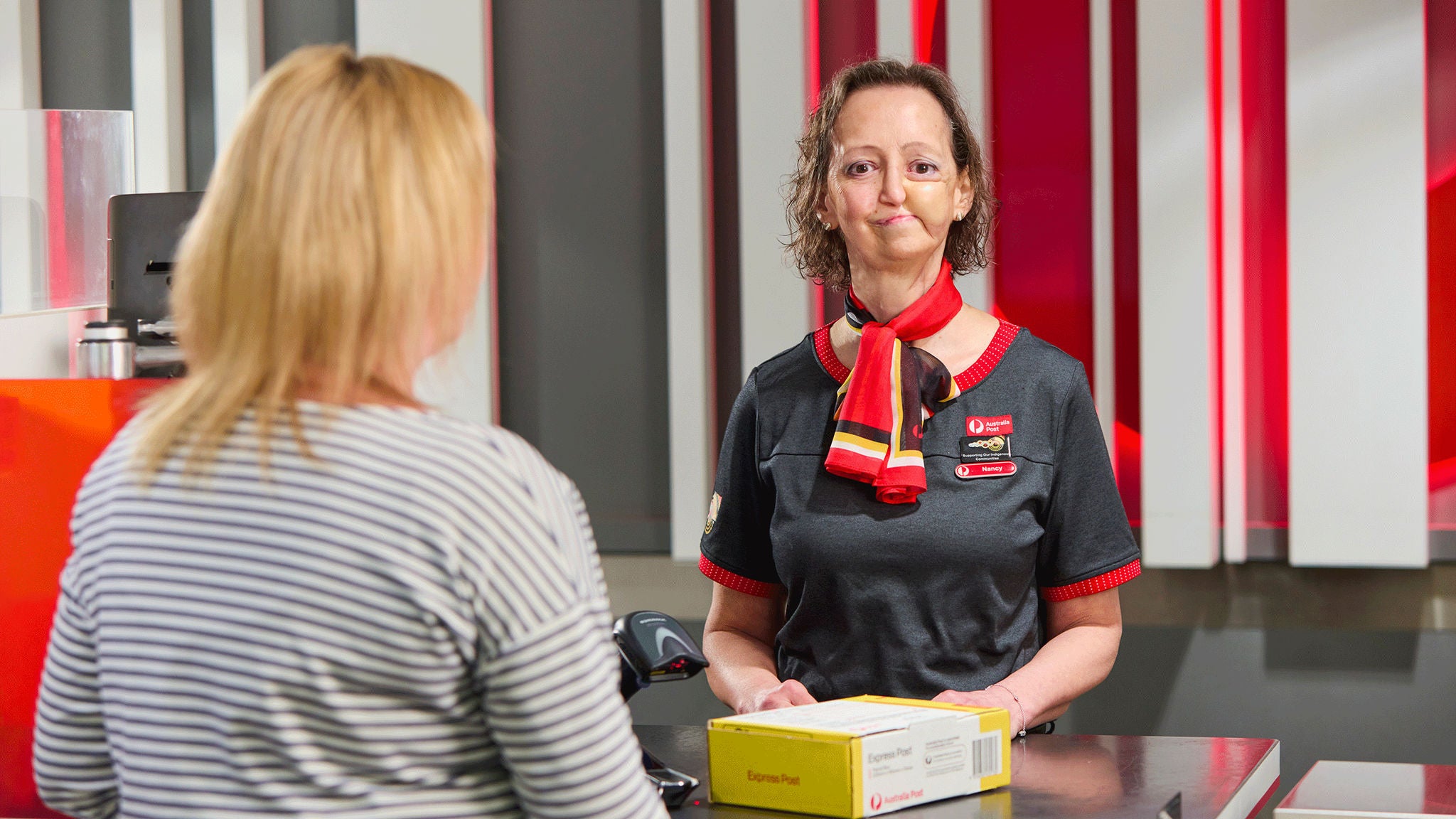 Photo of a female retail employee at counter helping customer