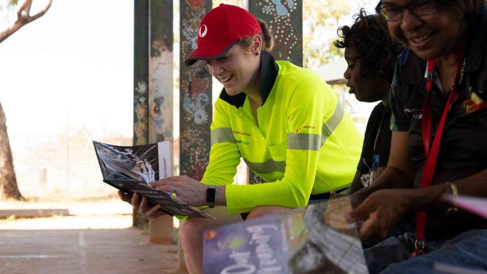 Australia Post team member celebrates national reconciliation week 2023 with indigenous community members.
