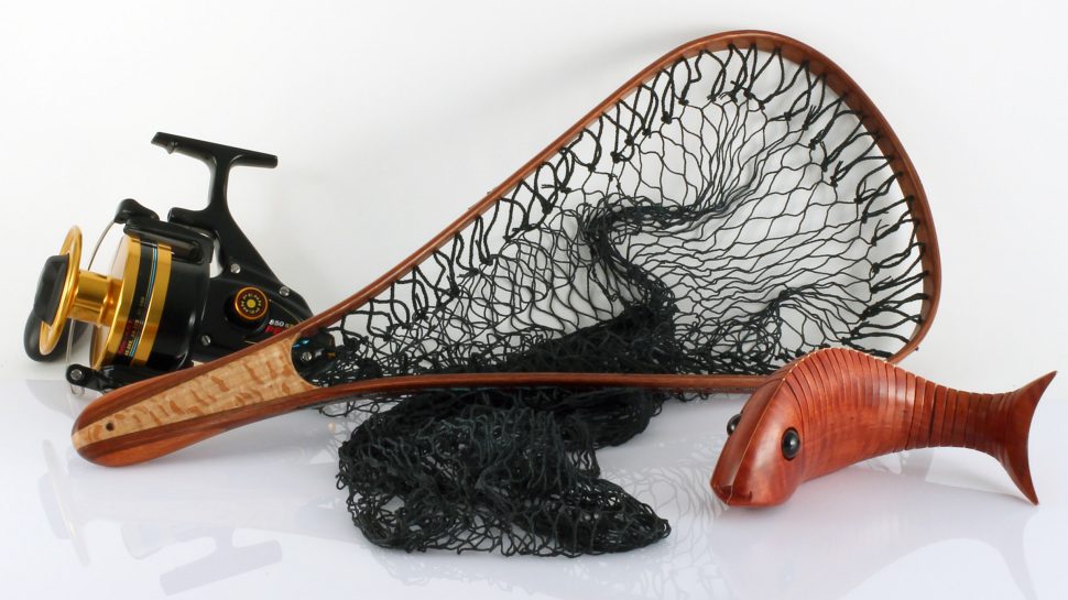 A wooden fishing net with a fishing reel and wooden fish beside it