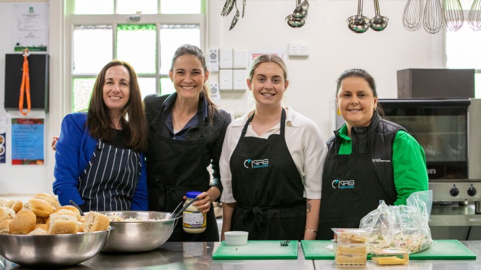 Four women wearing aprons in a kitchen.