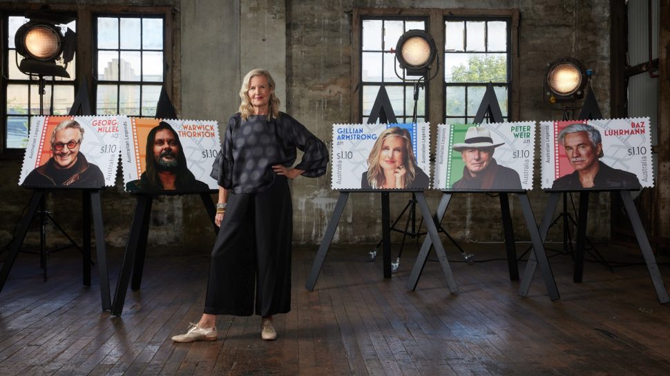 Gillian Armstrong standing next to the enlarged versions of the Australia Post Legends of Filmmaking stamp collection.
