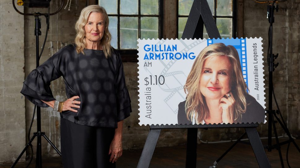 Gillian Armstrong standing next to an enlarged version of her Australia Post Legends of Filmmaking stamp.