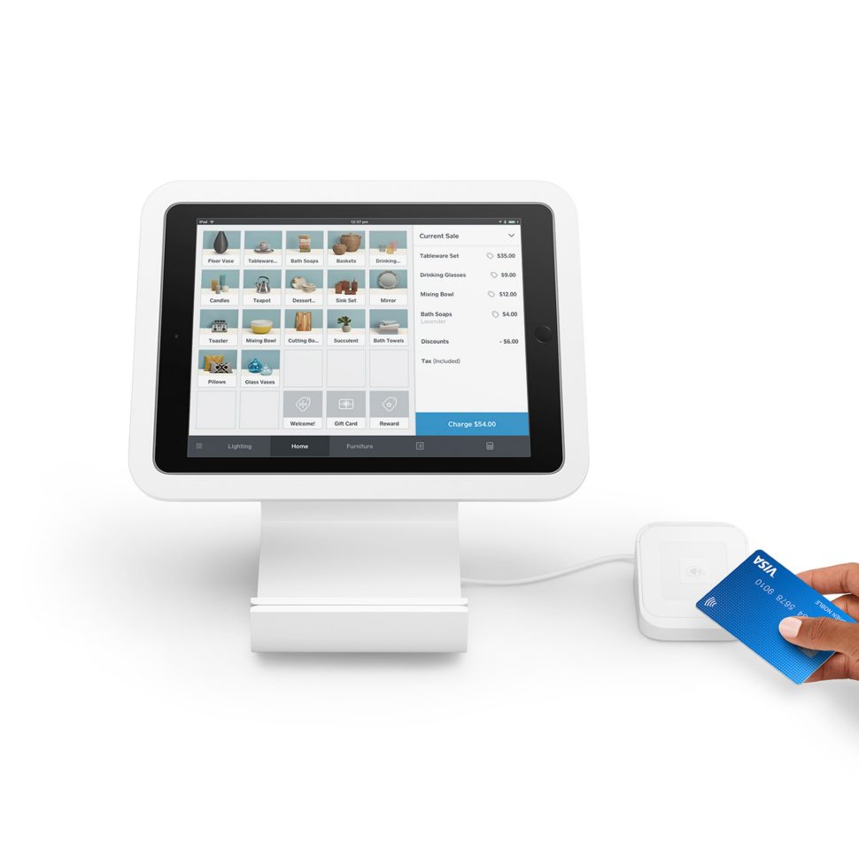 White iPad on stand with person’s hand holding payment card to reader.
