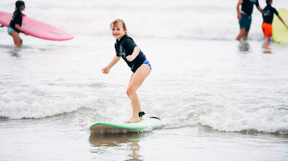 Young girl surfing close to the shore. 