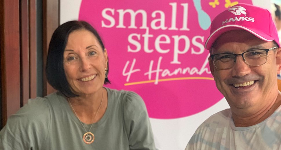 A man and woman smiling. Behind them is written ‘Small Steps 4 Hannah’