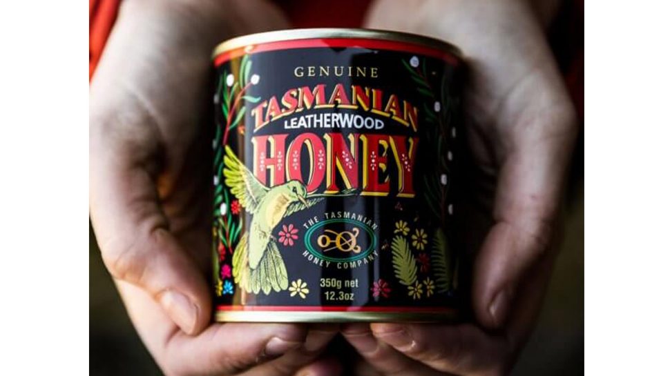 Hands holding a tin of Tasmanian leatherwood honey