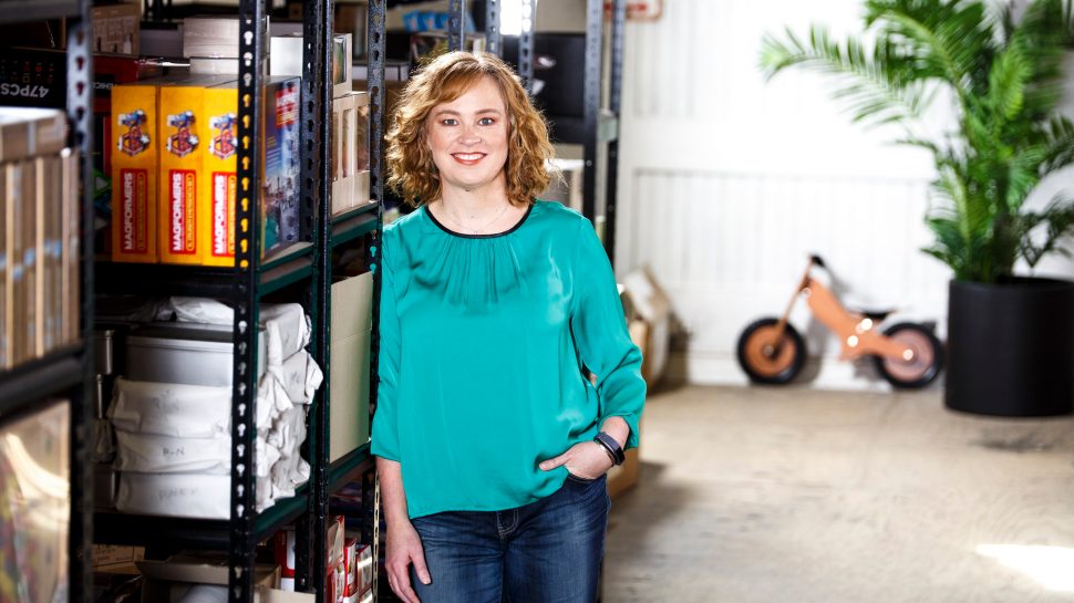 Helle Warming, the founder of Lucas Loves Cars, standing in front of a shelf filled with stock in her business warehouse in Melbourne. 
