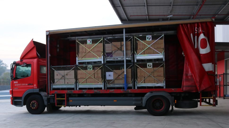 Red Australia Post delivery truck being filled with wine boxes.