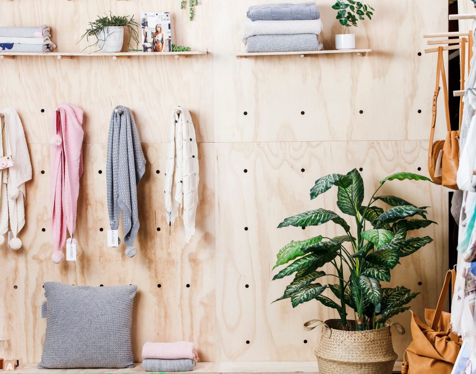 Six white dresses hang from a clothes rack in front of a white brick wall.