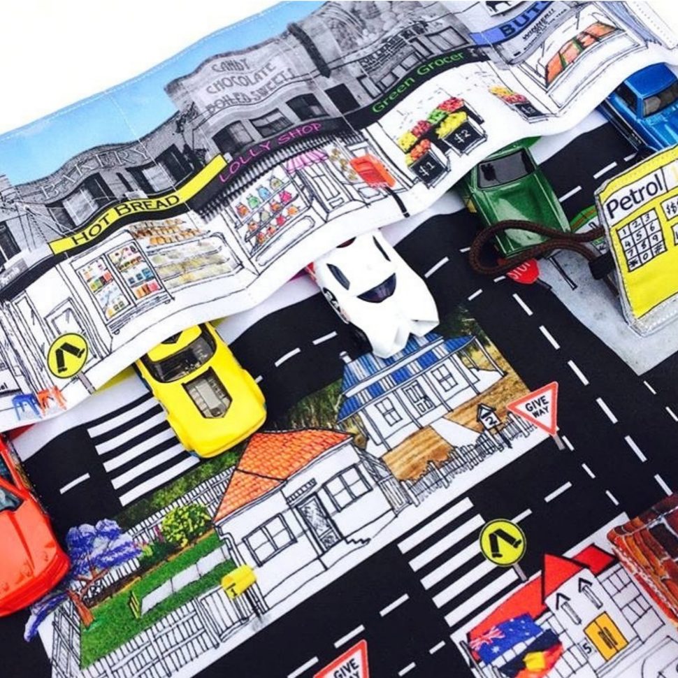 Close-up of a play mat, this one showing a street scene with toy cars.