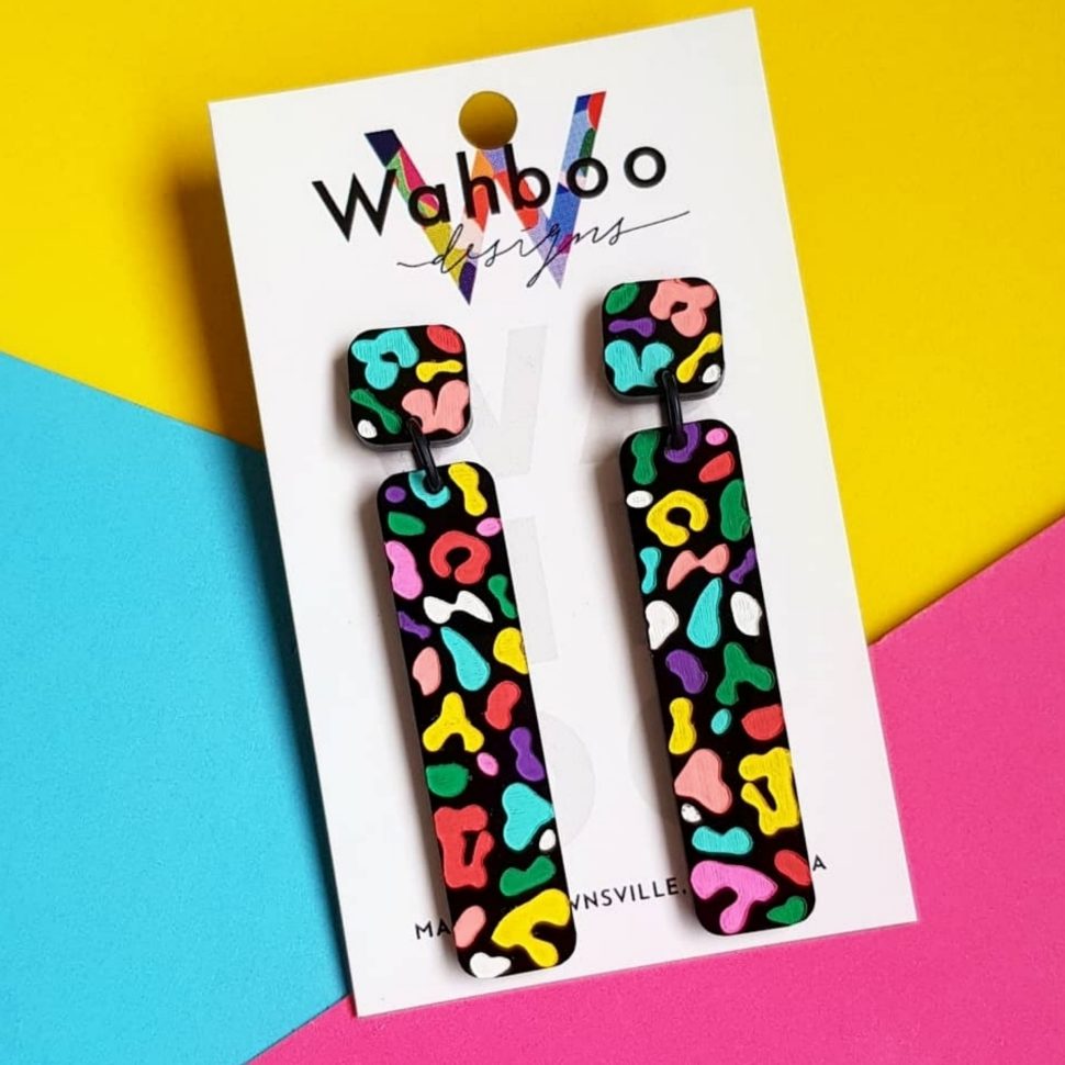Close-up of a pair of brightly-coloured dangly earrings with a squiggly pattern.