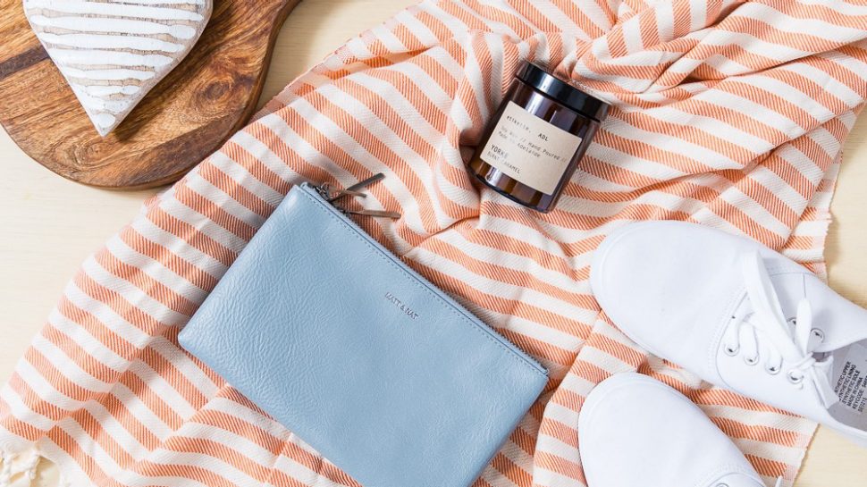 Flatlay photograph of a beautiful array of item: a cheese board, a card, a scarf, a wallet and some shoes