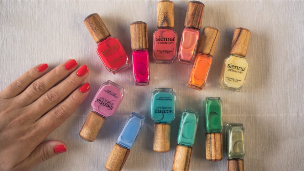 Collection of 12 bright nail colours and hand with nails painted in red.  