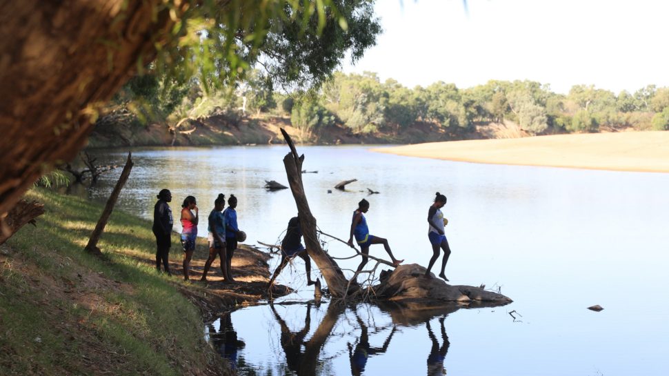 A group of young women from the Looma Lady Eagles AFLW team hanging out by the river 