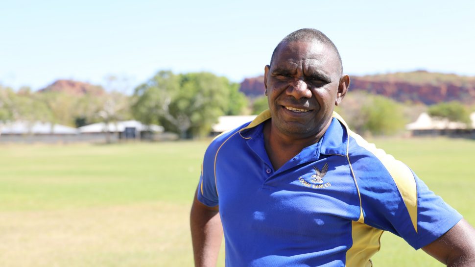 An Indigenous man wearing a blue T-shirt with the Looma Eagles logo on it 