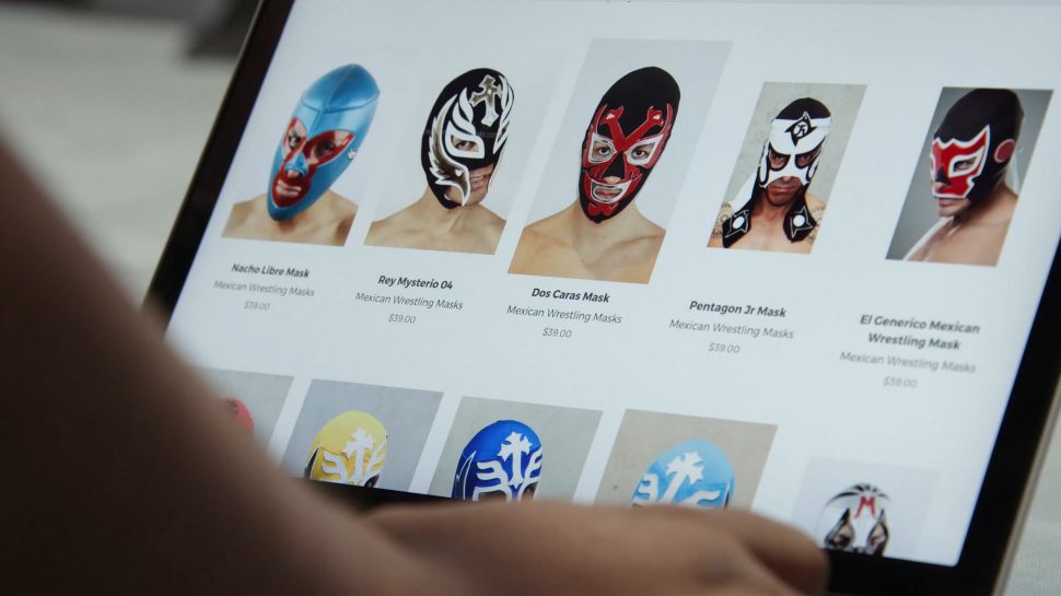 A person looks at a selection of Mexican masks on a laptop screen 