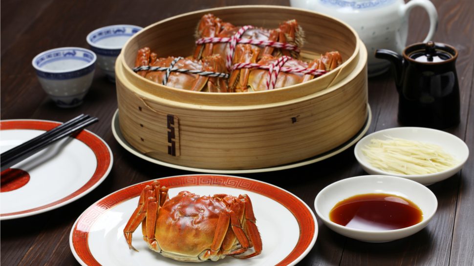 Close-up of table setting with cooked hairy crab in bamboo steamer.