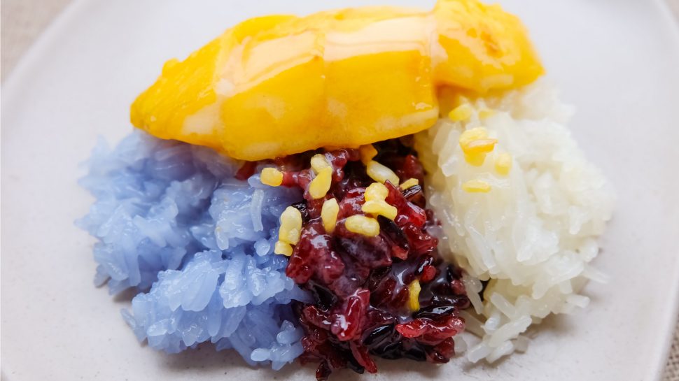 Close-up of sticky purple rice with coconut rice and mango.