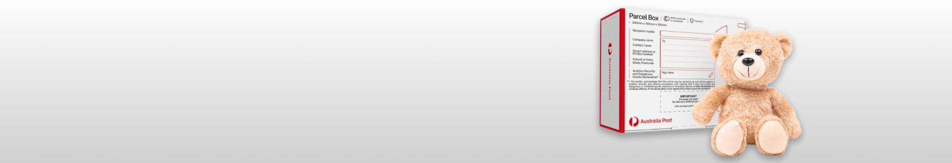 A light brown teddy bear sitting next to a medium sized Australia Post parcel box on a grey background