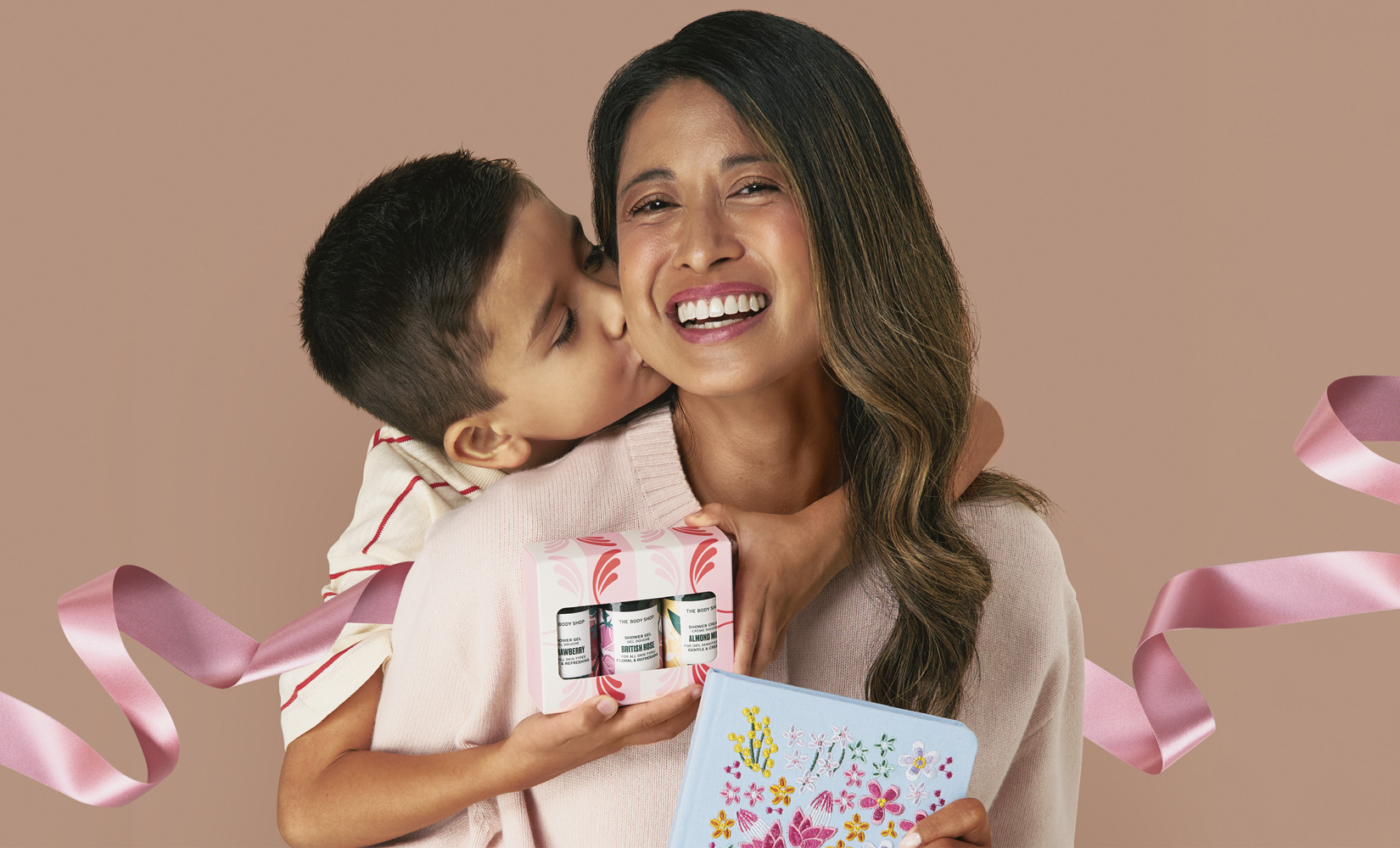A smiling mother with her child standing just behind her, both appearing happy and close.